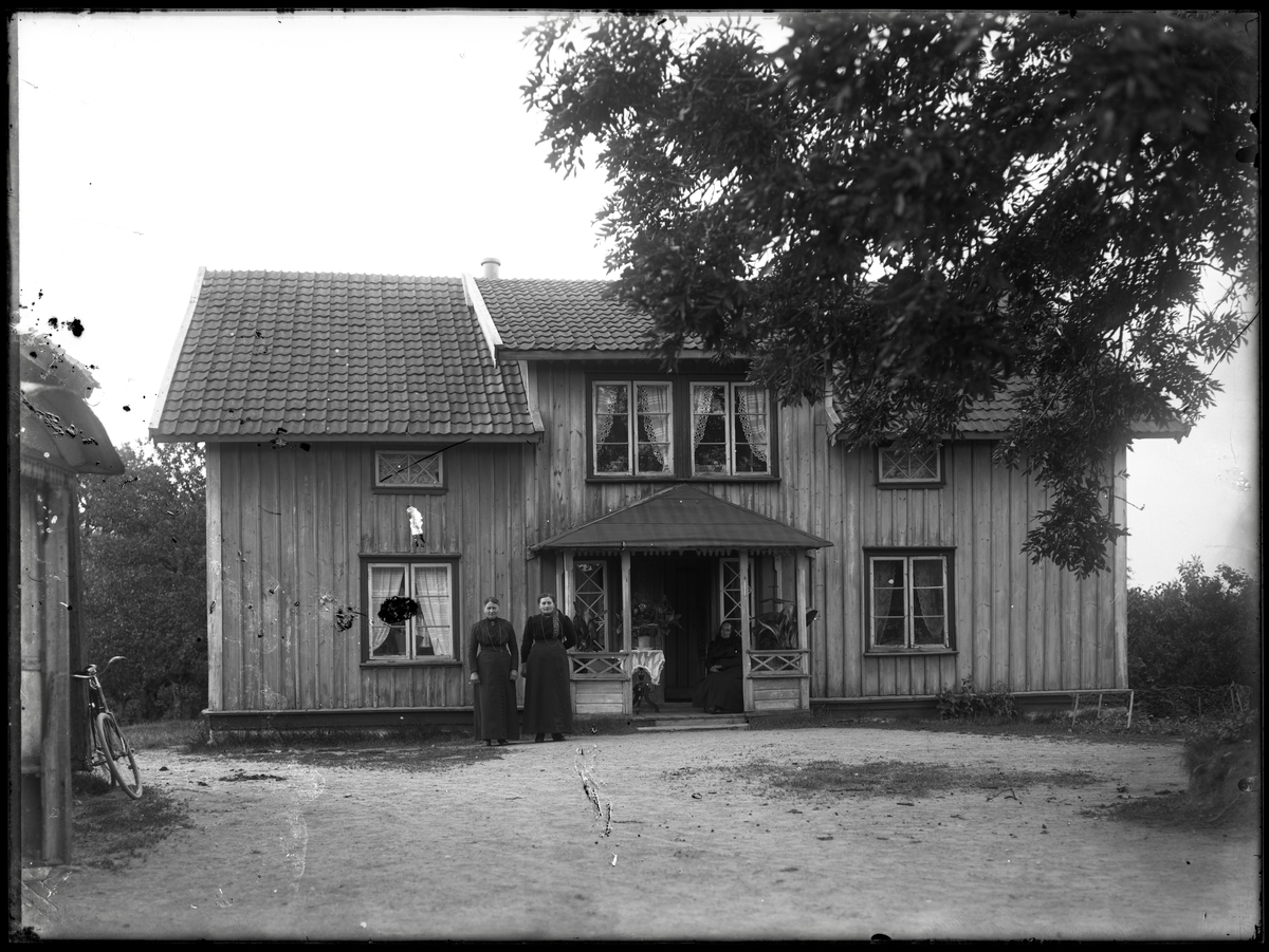 Gårdsfolk stående framför gårdshus