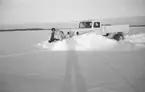 Snöplogning av havsis för upprättande av flygbana vid Svenska frivilligkåren i Finland, F 19. En militär sitter på plogen. Vy från sidan.