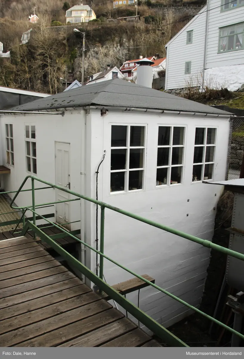 Del av produksjonslokala til Salhus Tricotagefabrik (1859-1989) bygd i 1918. Bygget inneheldt smia til fabrikken (1. etg) og mekanisk verkstad (2. etg.) I tillegg til tekstilarbeidarar hadde fabrikken lenge ein tilsett malar, snekkar, og nokre på mekanisk arbeid, som arbeidde på fabrikkanlegget og bustadane fabrikken eigde. Ein mekanisk verkstad gjorde det også mogleg å lage ein del delar sjølv, når det var behov for det.