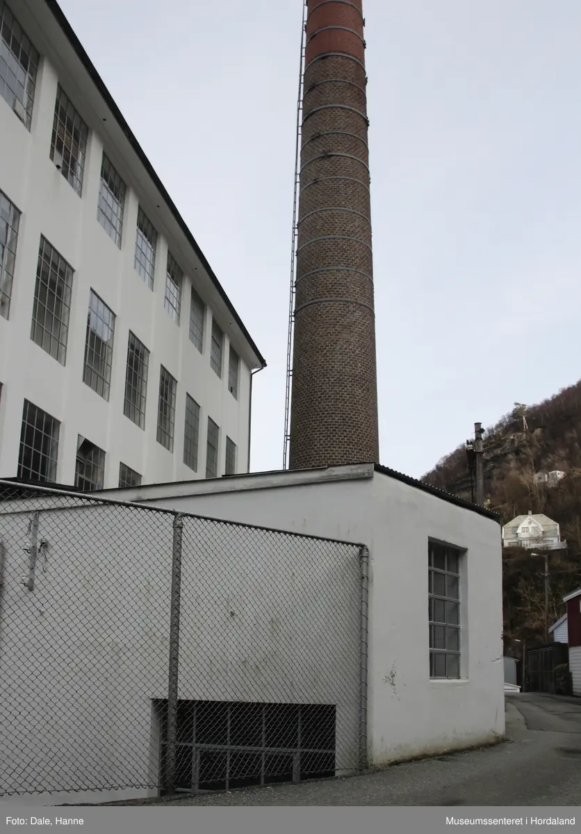 Del av produksjonslokala til Salhus Tricotagefabrik (1859-1989) bygd i 1903. Fyrhus og skorstein til fabrikken, med oljekjel i eitt rom, fyrkjel i den andre delen, og fabrikkskorsteinen.