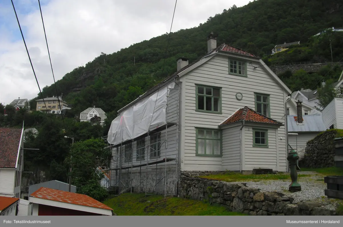 Den første arbeidarbustaden til Salhus Tricotagefabrik (1859-1989), bygd året etter fabrikken. Opphavleg inndelt i seks leilegheiter og sovesalar.