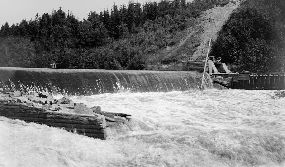 Syversætredammen eller Sjusætredammen i elva Flisa, ei sideelv til Glomma i Åsnes i Solør.  Fotografiet er tatt i 1916, fra nordre elvebredd, og fra en posisjon litt nedenfor den terskeldammen som var bygd øverst i fossen.  Her hadde elva et fall på cirka to meter.  Også nedenfor dette fallet rant vannet kvitskummende med et visst fall.  I forgrunnen til venstre ser vi enden av ei steinfylt tømmerkiste, antakelig en såkalt skådam som fungerte som avgrensning for et tømmerløp.  På motsatt side av elva ser vi en damkonstruksjon, sannsynligvis for inntaket for driftsvann til kverna som lå på den sørøstre sida av elva. Navnet på denne lokaliteten har vært stavet på forskjellige måter: Syversæterfossen. Syversæterdammen. Syversætrefossen. Sjusætrefossen.