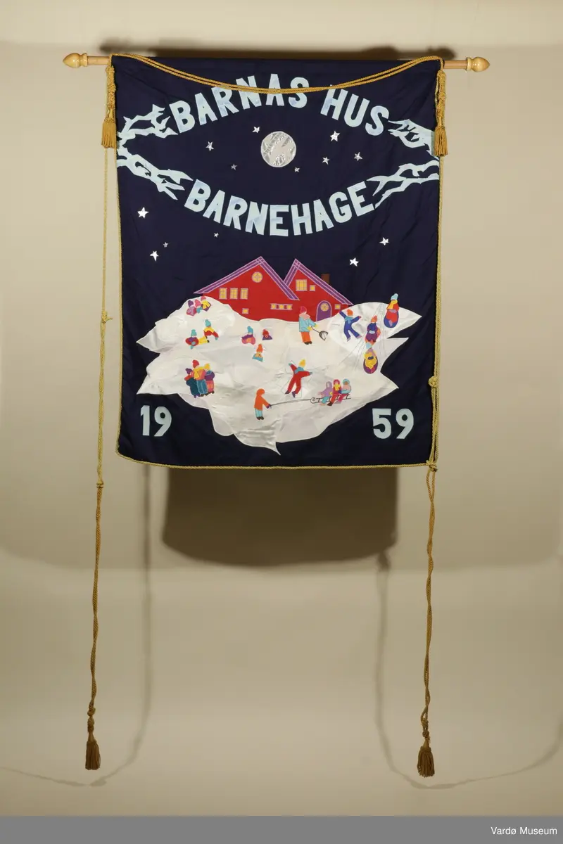 Barnas hus, fane for barnehage i Vardø. Motivet på fanen viser to hus, og foran huset er det et stort hvit område hvor barna leker.