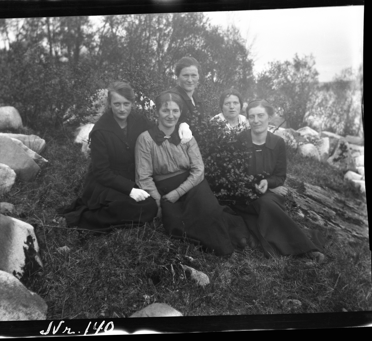 Gruppebilde av fem kvinner sittende i en skråning.