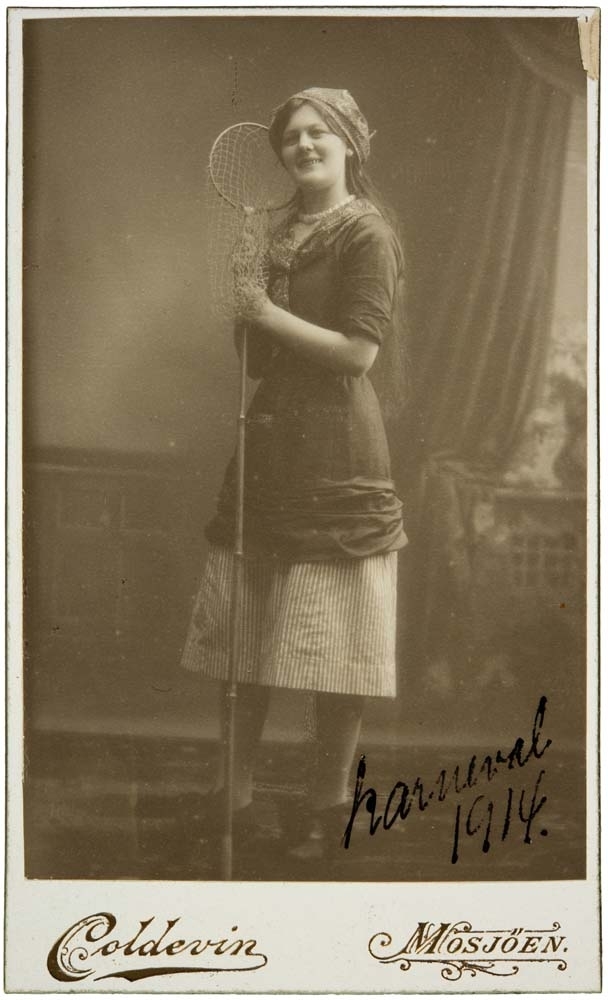 Visittkortportrett av kvinne i kjole som holder en håv.
Påskrift: Karneval 1914