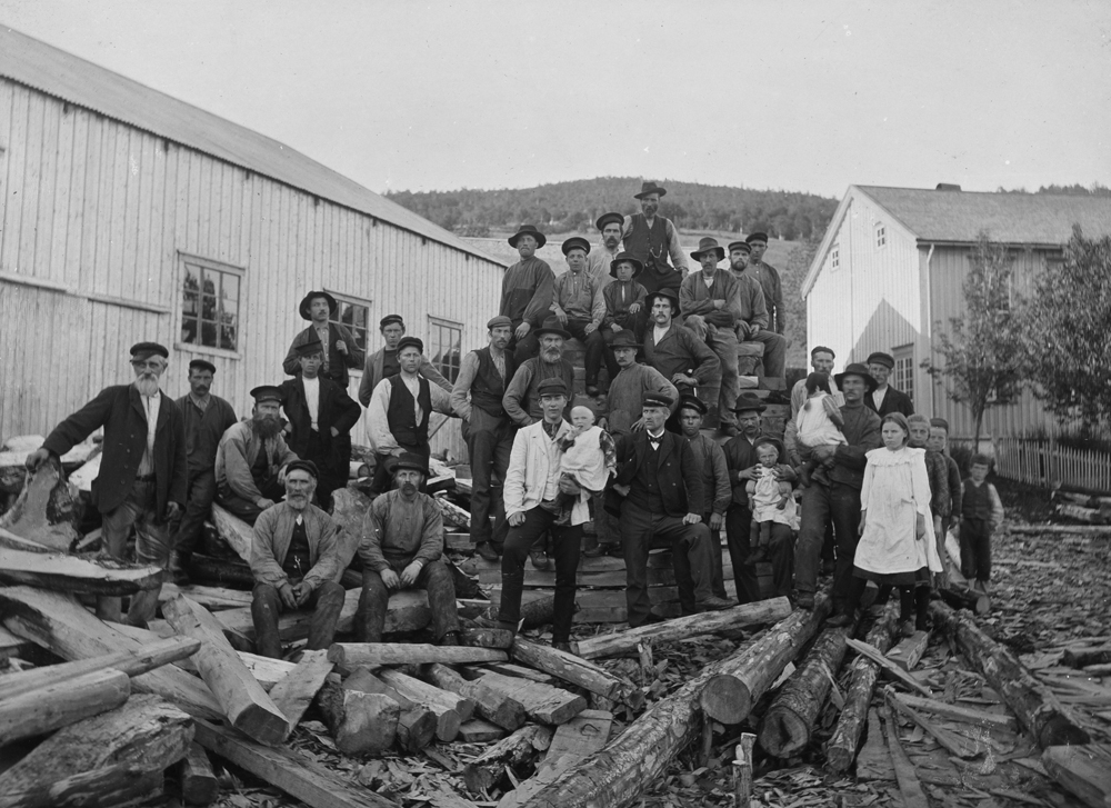 Skandfers båtbyggeri i Kulstadsjøen ca.1910. Arbeidsstokk og barn fra nabolaget omkranser mesteren Nils Skandfer i mørk dress t.h. for barnet  på armen,