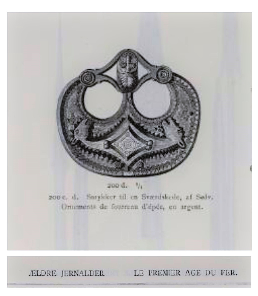 Sølvbeslag og en liten del av dens festeinnretning, forgylt med nielloinnlegg, som type R. 200 d fra eldre jernalder. Utsmykning til sverdslire. Funnet i en gravhaug på gården Mellom-Kvem.