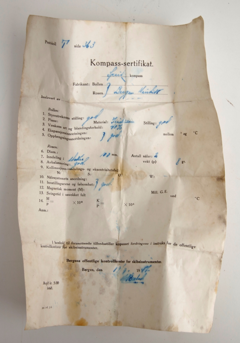 Kompass i trekasse med lokk. Kompasset sitter fast i kassen med to festepunkter. Kompasset kan vippes alle veier. Rundt lesehus. Et dokument fulgte med kassen: "Kompass-sertifikat".