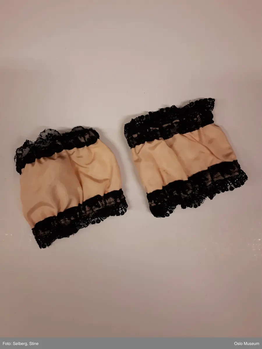 Halvlang rosa ballettkjole i silke med sorte blonder og to løse små ermer, samt et par svarte ballettsko med svarte bånd.
A: Kjole
B: Løst erme
C: Løst erme
D: Ballettsko
E: Ballettsko