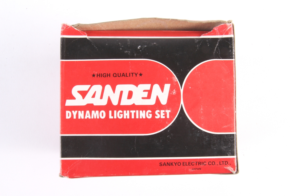 Sett med sykkellykt og dynamo i original emballasje. Sykkellykt har en rektangulær avrundet form og to lyspærer innvendig.