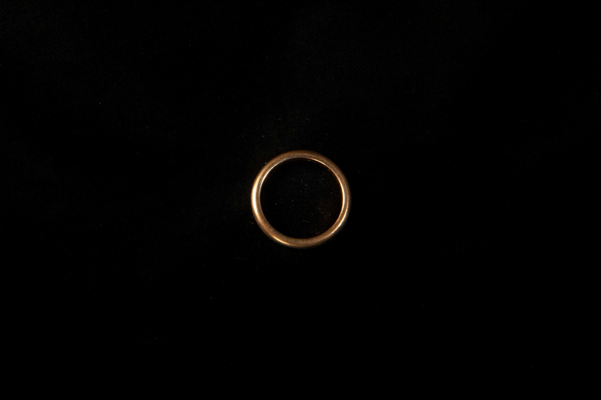 Fingerring av gulddoublé, slät. Ligger i en rödklädd pappask, invändigt klädd med grön sammet. På undersidan av asken står "Min mammas ringar".