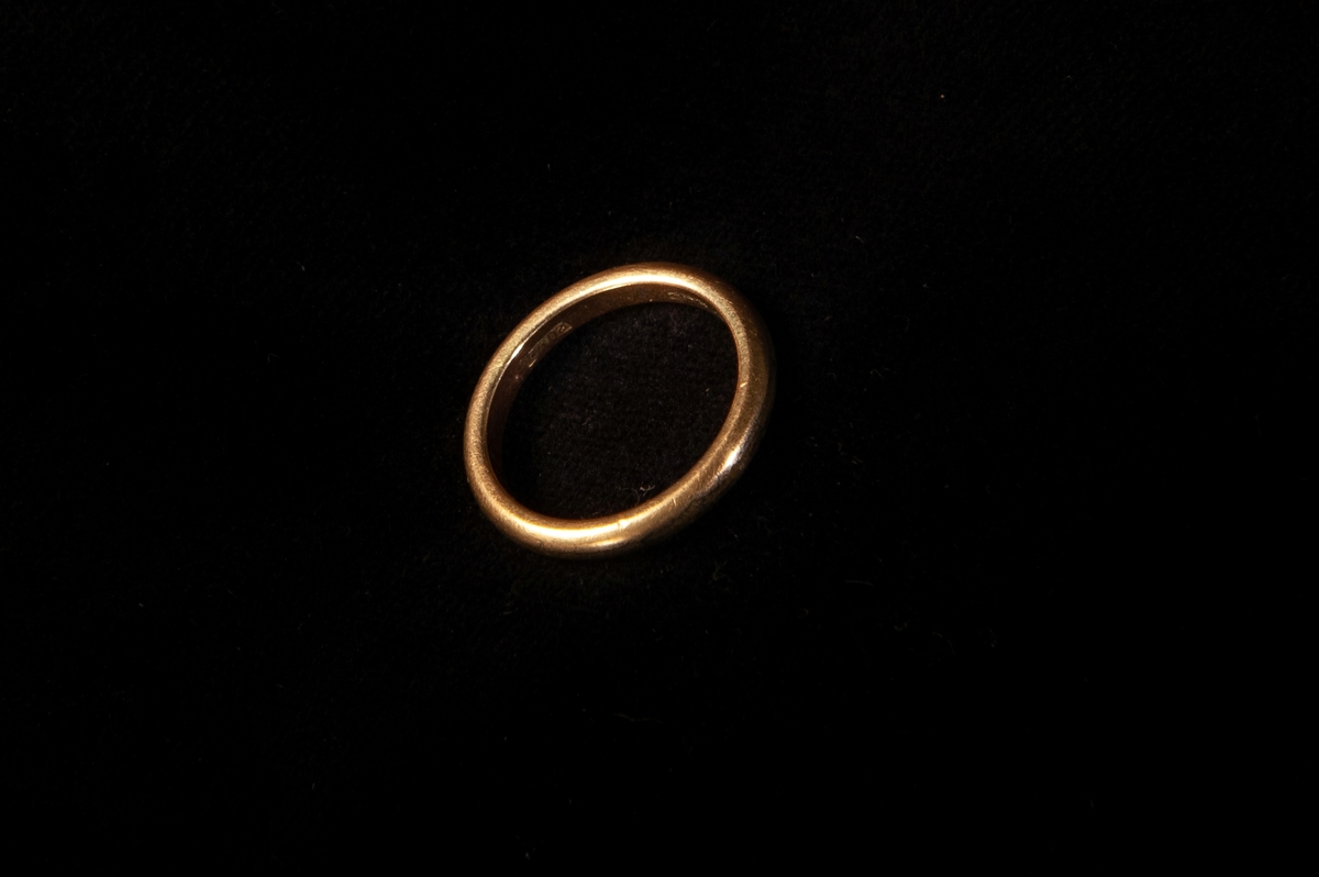 Fingerring av gulddoublé, slät. Ligger i en rödklädd pappask, invändigt klädd med grön sammet. På undersidan av asken står "Min mammas ringar".