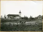 Hed sn, Hed kyrka.
Kyrka och bostad i bakgrunden. I förgrunden åker och en man med hästkärra.