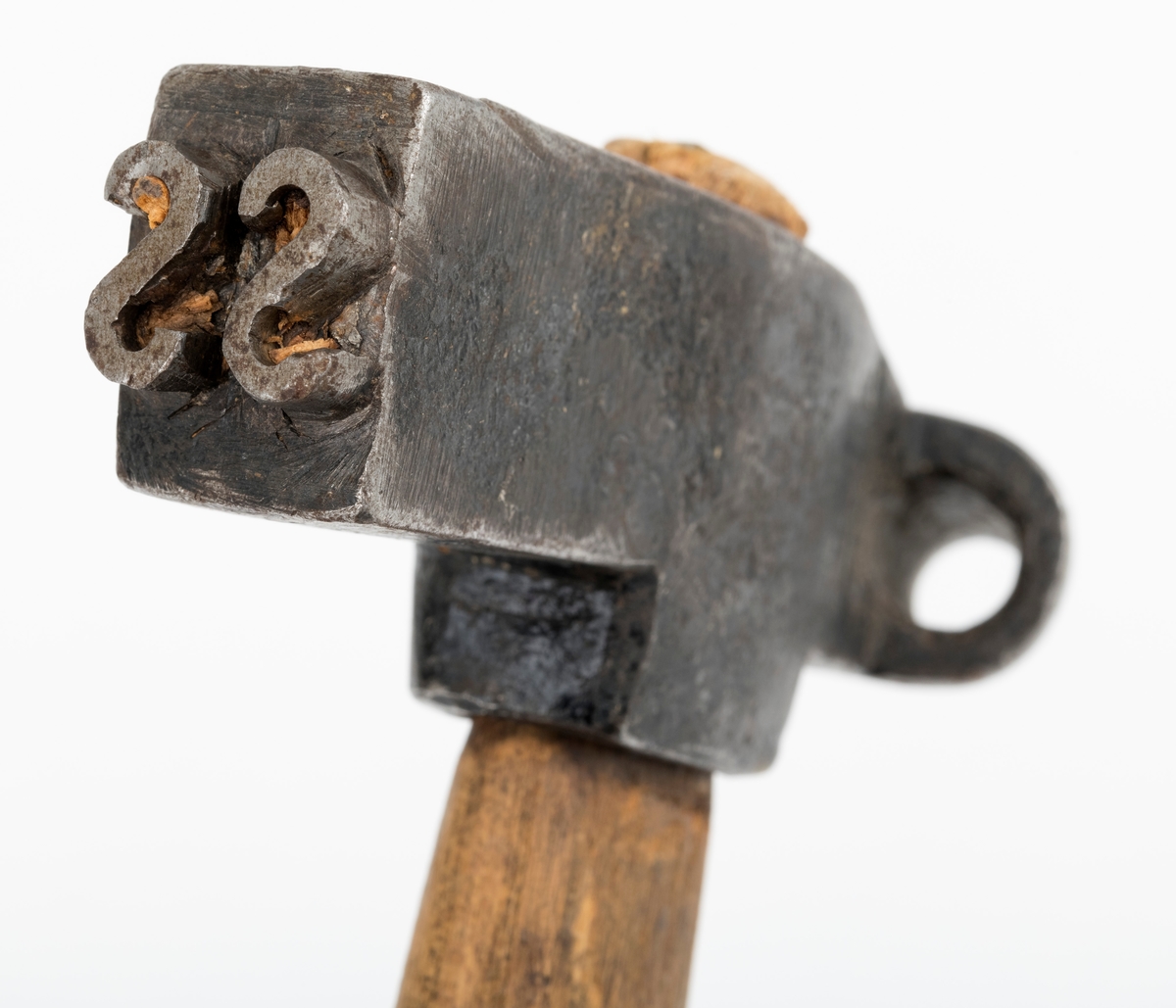 Avkortingsøks. Til øks å være, er dette et lite eksemplar med en hammer som er 12,6 centimeter høy og som har rektangulært tverrsnitt. I den ene endeflata er det to speilvendte S-er i opphøyet relieff (cirka 4 millimeter). Disse ble antakelig slått inn i endeveden på tømmerstokkene. I den andre enden av øksehodet er det en utsmidd stålsko som er 2,3 centimeter høy. Økseprofilen ble slått inn i stokkenes yteved, der den etterlot seg et sirkelrundt merke med diameter på cirka 1,2 centimeter (1/2 tomme). Slike merker ble brukt til å markere lengde på avkortinger som ble foretatt i forbindelse med innmåling og annamming av tømmer. Bakgrunnen for slike avkortninger kunne være skader eller feil, for eksempel på grunn av råtepartier eller vekstkrumninger som gjorde deler av stokken verdiløsr i skurlastproduksjonen. 

Øksa har rett 33,1 centimeter langt skaft av ubehandlet ask. I den fremre enden er det innslått en jernkile som skulle bidra til at øksehodet satt godt på skaftet når redskapet var i bruk.

I museets aksesjonsprotokoll har man antatt at de to S-ene er initialene til Steinkjer skogskople, som har overdratt gjenstanden til Norsk Skogbruksmuseum.