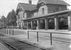 Båstad Södra järnvägsstation, ursprungligen uppförd 1885 av Skåne Hallands Järnväg, SHJ. SHJ förstatligades 1896 och stationen tillbyggdes av SJ med bl a övervåning vid sekelskiftet. Loggian, pelargången, till höger tillkom 1935, då också expedition, biljetthall och resgodsmagasin byggdes ut.