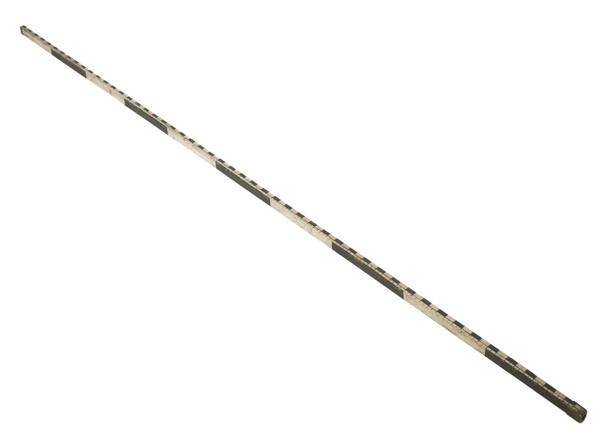 Rutestokk, malt i sorte og hvite felter, 1 fot og 1 1/4 tomme. Målets lengde 10 fot.Beslag av messing i begge ender