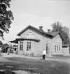 Örbyhus stationshus från gatusidan. Tvåaxlig rälsbuss. Trafikplatsen öppnades 1874. På 1950-talet byggdes ny stationsbyggnad som syns på bilden. Ett tvåvåningshus i trä.