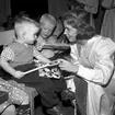 Luciatärnan Ulla delar ut julklappar på ett barnhem för föräldralösa barn, Hauptkinderheim in Ruhleben, i utkanten av Berlin i samband med Statens Järnvägars, SJ, luciabesök i Berlin 1958