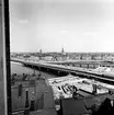 Expresståg på Riddarholmsbron, vid driftplats Mälarstrand, på väg mot Riddarholmen.  Tyska kyrkan även i bild.
Fotot möjligen taget från taket på fastighet Pryssgränd/Bastugatan.