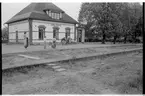 Stationshuset i Åsbo-Össjö. Stationen nedlagd 1953-06-10. Barn med motorcykel på plattformen. Spåren är borttagna.