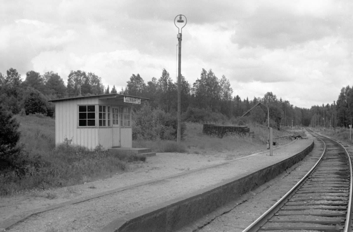 Hållplatskur från Tjunnaryd. Målad i ljusgul kulör med ljusgrå dörr, dörrfoder och fönsterfoder. Spröjsade fönster utmed hela framsidan, även på dörren, och delvis på sidorna.