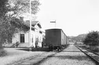 Nelhammar järnvägsstation. Personal utanför stationshuset och ett tåg på spåret.