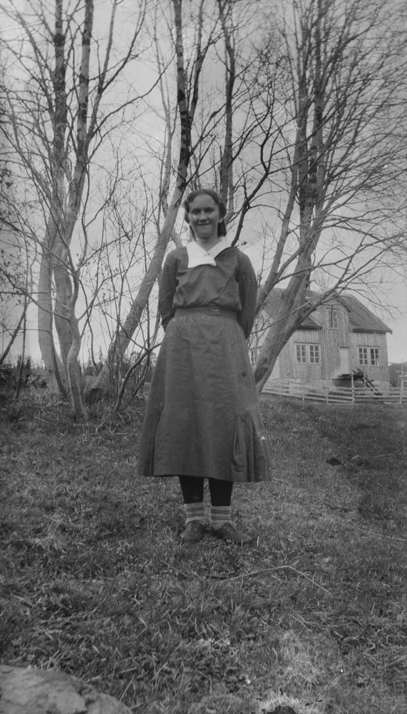 Portrett av Jenny Bessedør. Hus i bakgrunnen.