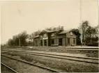 Station anlagd 1866-67. Stationshuset, tvåvånings i trä, tillbyggdes i båda ändar 1899 och i dessa tillbyggnader rymdes expedition samt 2 klass väntsal. Bangården har utbyggts i tre etapper, senast i samband med elektrifieringen 1949. . HLJ passerade UWHJs spår i plan på bangården 
HLJ , Lidköping - Håkantorps Järnväg
UWHJ , Uddevalla - Vänersborg - Herrljunga Järnväg