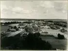 Ett sommarfoto. Utsikt från kyrkotornet mot norra Ockelbo. Kyrkan byggdes på 1200-talet. Den medeltida kyrkan revs 1795  då påträffades en runsten inmurad i grunden.  I samband med kyrkbranden 1904 förstördes stenen. En kopia utfördes 1932 efter avbildningar från 1880-talet.