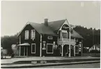 Ullared station. Det står några koffertar mellan spåren, barnen sitter till vänster om stationen.