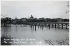 Arbetsbrygga för pålningsarbete för byggande av bro över Ätran. Falkenbergs gamla kyrka, S:t Laurentii, syns i bakgrunden.