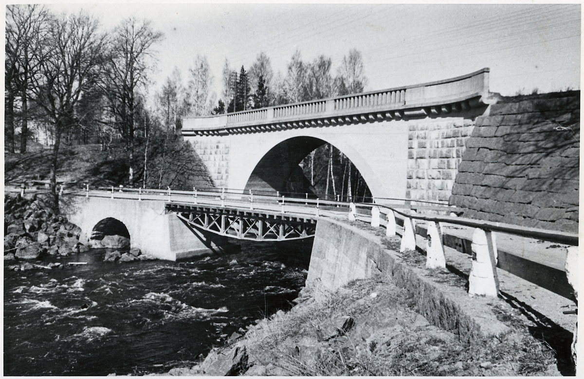 Parallella broar över Arbogaån strax väster om Frövi i Örebro län.
Järnvägsbron som är den övre/bakre i bild ersatte 1913 den gamla bron som då var den andra på platsen. Den kompletterades 1954 på andra sidan med ett spann för dubbelspår.
Vägbron på hitsidan är ersatt sedan man dragit om vägsträckningen och byggt en ny bro en bit nedströms.
Tillfarterna till den gamla bron hade bl a alldeles för tvära kurvor. Landfästena finns dock fortfarande kvar.

Källa: sid 72 - 73 i boken Våra broar – en kulturskatt, av Ahlberg och Spade.