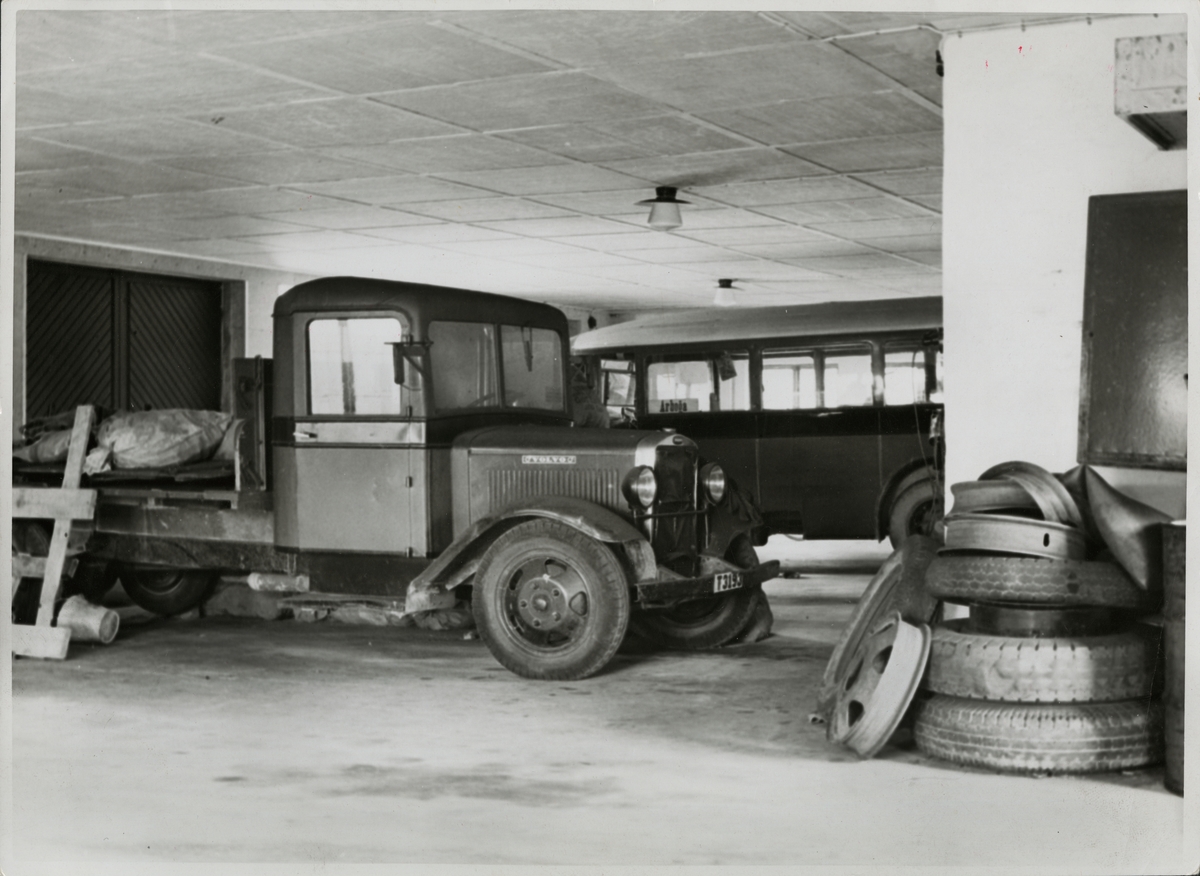 Lastbil och buss i garage. Lastbilen är en Volvo med registreringsnummer T3193 och bussen har en skylt för Arboga.