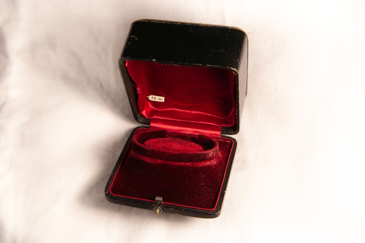 Ett armband, tätt besatt med slipade röda granater. Infattade i förgylld metall, troligen silver. Armbandet något avsmalnande åt sidorna.Smycket ligger i specialgjord svart, ask med röd sammet invändigt och ett snäpplås. 
Inga stämplar på armbandet.
