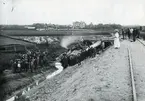 Gruslastat tåg som spårat ur på väg till Edsbyn. Järnvägen var 1900 nybyggd. Vid olyckan fick en man sin ena arm avsliten. I bakgrunden ses 