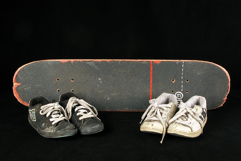 a) skateboardbräda av trä. Hjul saknas. Mått: längd 77,5 cm, bredd 19 cm, tjocklek 1 cm.
b1-b2) svarta skateskor. Märke: DC Shoe.
Märkning: "DCSHOECOUSA".
 Mått: längd 23 cm, bredd 9 cm, höjd 8,5 cm.
c1-c2) vita skateskor.  Märke: DC Shoe. 
Märkning: "DCSHOECOUSA". 
Mått: längd 22 cm, bredd 8, 5 cm, höjd 8,5 cm.