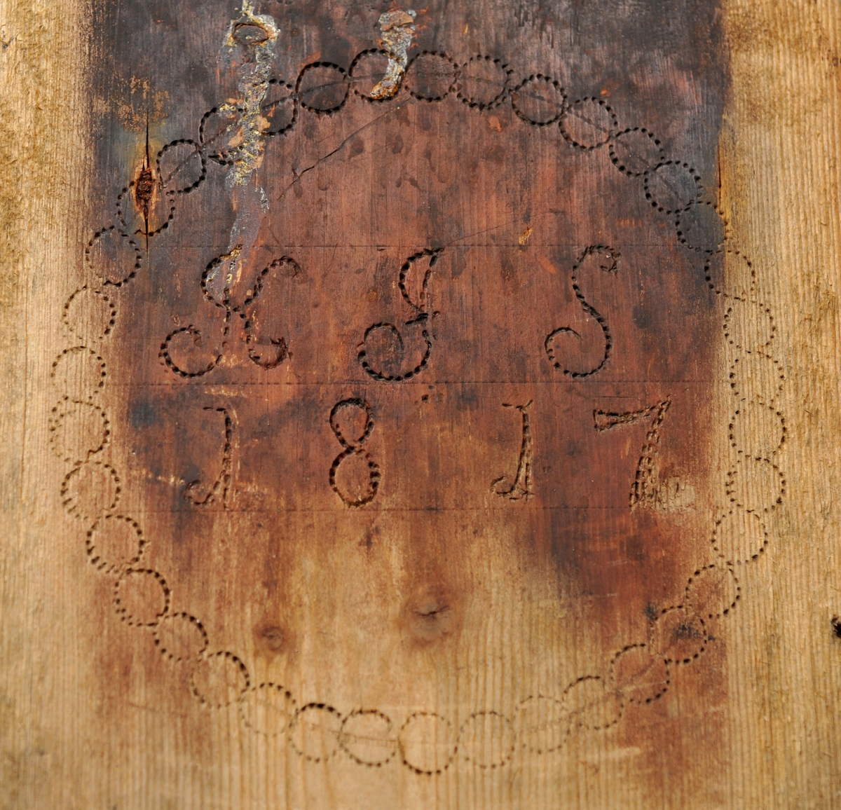 Sveipet laup med rett bakstykke, lagd for å kunne henges på en vegg, der den skulle henge som en beholder, opprinnelig sannsynligvis på et kjøkken. Sett rett ovenfra eller nedenfra er laupen formet som en halvoval. De veggene som skulle vende fram i rommet er lagd av tre forholdsvis tynne (7-8 millimeter) bjørkeskier, som er bøyd i en U-form. Endestykkene er festet i slisser langs kantene av bakstykket ved hjelp av trenagler. Disse tre komponentene er bundet sammen, kant mot kant ved hjelp av bindsler av trefibermateriale. Ytterflatene har svidekor - bølgemønstere på den øverste og nederste, og en akantusranke på den midtre, som er noe bredere enn de to andre. Bakstykket - ryggfjøla - er lagd av et 21,3 centimeter bredt og 1,9 centimeter tjukt (3/4-toms) bord, antakelig av granvirke. Det er vinkelrett avkuttet i den nedre enden, men overenden er avrundet og profilert. Her er det fire gjennbombrutte hull, hvorav tre er runde og det fjerde er firefliket. Det øverste av disse har vært brukt ved oppheng. Også denne delen av laupen har svidekor med elementer av de samme formene som finnes på veggenes forsider. På baksida er det innsvidd en ring, sammensatt av små sirkler, som omgir initialer og årstall: «KSS 1817». Forsida er svijernstemplet «Jh. HØYE». Laupen har et halvovalformet lokk, lagd av granvirke og prydet med et innsvidd mønster, bestående av sirkler, halvsirkler og akantusblader. Også her finner vi det nevnte svijernstempelet. Lokket og bakstykket kan se ut til å ha vært innsatt med et rødbrunt fargestoff. Opprinnelig hengsling mangler. Botnstykket mangler fullstendig, men et innfelt spor nederst på bakstykket og naglehull langs ytterkanten på den nederste buete skia antyder hvordan botnstykket har vært festet.