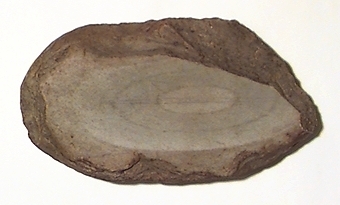 Malsten, av sandsten, oval, platt. Oval även i tvärgenomskärning. Med två konkava slipytor belägna mitt emot varandra på plattsidorna.