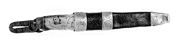 Tollekniv med slire.  Knivens lengde er 20 centimeter.  Den har et gulkvitt beinskaft, som er 10,7 centimeter langt og har et noe konvekst lengdesnitt og et noenlunde ovalt tverrsnitt.  Midten av skaftet måler 2,7 X 2,1 centimeter.  Overflata er prydet med et akantusrelieff.  Langs skaftryggen er det et glatt felt med initialer og årstall: «N P S F[?] 1887».  Det er nærliggende å anta at dette må ha vært en tidligere eiers initialer og anskaffelsesåret.  Beinskaftet har hatt messingholker i begge ender, men bare framholken (nærmest bladet) var intakt da kniven kom til museet.  Den er 1,1 centimeter bred og prydet med linjer langs ytterkantene, ellers glatt.  I overenden av skaftet later det til at ytterspissen på bladtangen er gjenget og påskudd ei kvadratisk mutter med skrådde sideflater.  Bladet er 8,6 centimeter langt og 2,3 centimeter bredt ved brystningen.  Videre framover er imidlertid bladet betraktelig smalere, på grunn av gjentatt sliping.  Den bakre delen av knives nakkeparti er 0,5 centimeter tjukk.

Slira er utført i lær med holker av messing og vedhengslet stropp for knappefeste i bukselinninga.  Samlet lengde er 27,8 centimeter.  Sjølve slira er 16 centimeter lang, fra enden av doppskoen til overkanten av munningsholken (målt på framsida, ikke hengslingspunktet bak).  Slirelæret er mørkebrunt og sammensydd med en søm som er plassert på «baksida», altså den sida som skulle vende inn mot bærerens kropp.  Framsida av doppskoen er merket med årstallet «1851», altså en datering som overgår den vi finner på knivskaftet med 36 år.  På baksida av doppskoen er det inngravert et symmetrisk akantusmønster med C-ornamenter.  Doppskoen er naglet fast i slirelæret ved hjelp av ei gjennombrutt nagle.  Akantusmønsteret fra doppskoens bakside finne vi igjen også på midtholken, som er drøyt 1,8 centimeter bred.  Ettersom holkene ikke er forbundet ved hjelp av sideskinner er også midtholken forankret i læret ved hjelp av nagler på sliras bakside.  Overholken eller munningsholken er 1,9 centimeter bred, og har samme akantusmønster som midtholken og baksida av doppskoen.  Også her er det naglefester i slirelæret.  Munningsholken har en sprekkskade, egentlig et brudd, på det som framstår som baksida av slira.  Her finner vi også et hengslingspunkt med ei U-formet bøyle som danner overgang til ei 4,5 centimeter lang og 1,5 centimeter bred messingspenne.  På forsida av denne spenna er det akantusdekor, på baksida finner vi initialene «B C L».  Spenna må ha vært beregnet på feste av knivslira i linninga på bærerens bukse.  Da kniven ble overlatt til museet var den imidlertid utstyrt med ei lærhempe med en splitt som kunne tjene som festepunkt på en knapp.