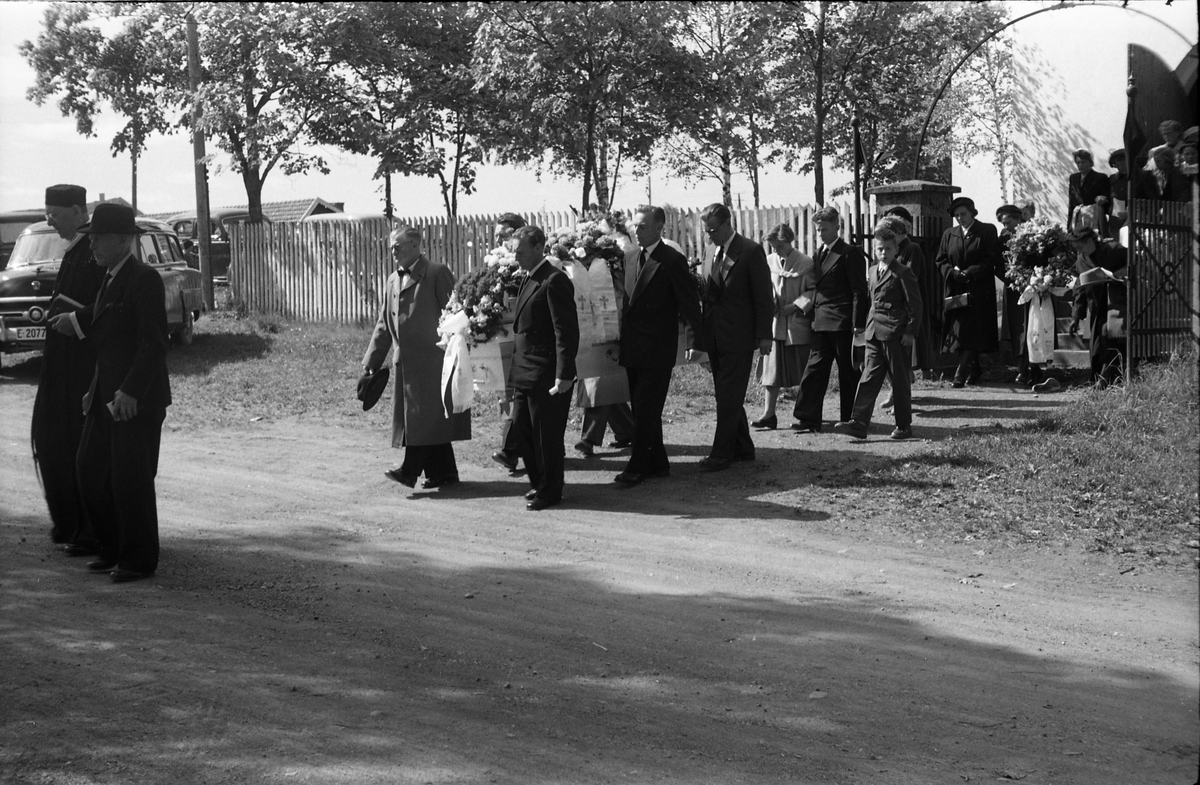 Begravelse ved Hoff kirke juni 1955. Serie på 9 bilder, der de første viser prosesjonen fra gravkapellet il grava, de øvrige ved grava. Ifølge informmant er dette begravelsen etter Ludvig Madshus som var kjøpmann i Lillo. Foraan prosesjonen går presten, som trolig er Finn Sommer, og kirketjener Pål Rødset. Nærmest bak kista trolig Ludvigs hustru Helga født Hagen, og deres to sønner Johan Ludvig (i midten) og Olav. De øvrige er ukjente.