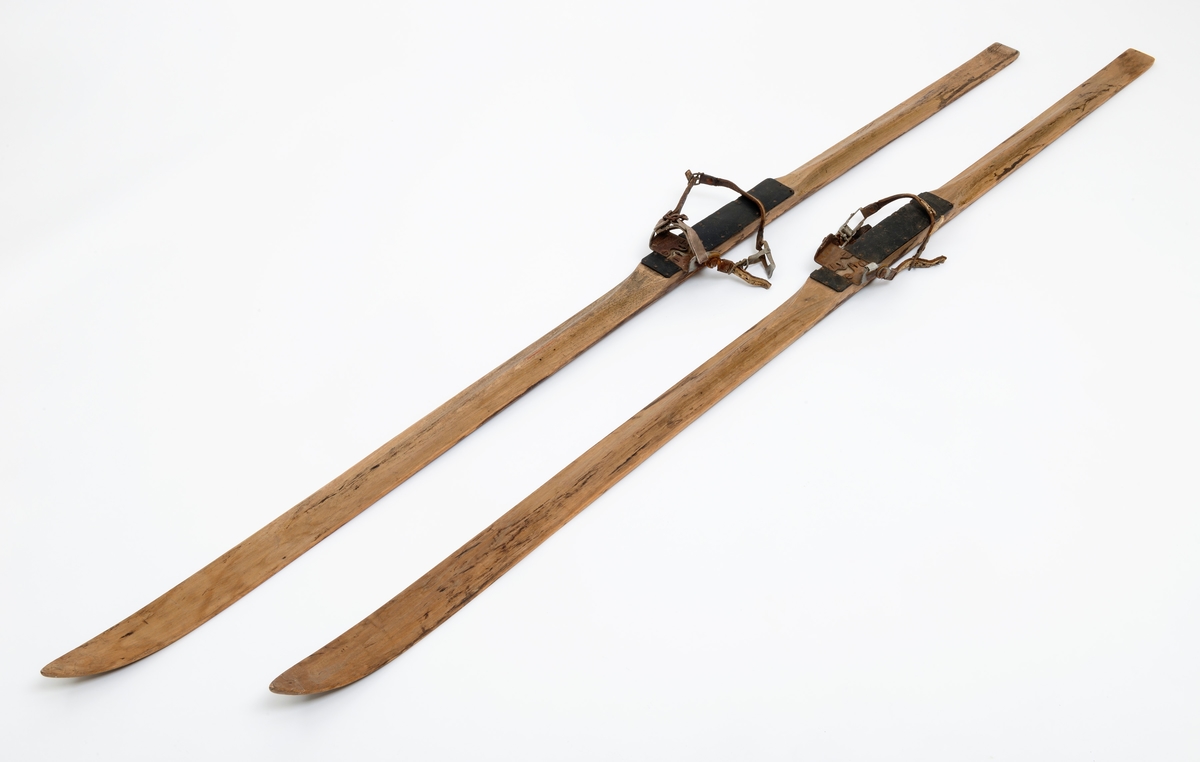 Skiene er brukt av Erik Andersson, Moelv, for å komme fram til fiskeplasser på Mjøsa. Skiene har bindingen av typen "Gresshoppa" no. 1, og er en tåbinding med bakbinding. Skiene er heltreski av hickory. De er 213 - 213,5 centimeter lange, målt i rett linje mellom bakender og tupper. Bredden foran, der hvor krumminga mot tuppene begynner er 7,3 - 7,4 centimeter. På midten, ved «fotstegene», der støvlene til skiløperen skulle festes, er bredden 6,1 centimeter, og i bakendene er breddemålet 6,5 centimeter. Sistenevnte mål er tatt cirka 4 centimeter framfor endene, som her er noe innsvingte. Tjukkelsen der hvor krumminga mot tuppene starter er 7-8 millimeter. Ved fotstegene er skiene om lag 3,0 centimeter tjukke, og i bakendene 1,4 centimeter. Langs midtaksene på sålene er det høvlet 1,5 centimeter brede styrerender. Oversidene av skiene er planhøvlete fremst, mot tuppene, og på fotstegene. Mot fotstegene har overflatene markerte, avrundete midtrygger. Skiene har bindinger med tåjern, bestående av to vinkeljern som er fastskrudd med en innbyrdes avstand og innbyrdes vinkler som skulle passe til den fremre delen av støvlesåla til skiløperen. På yttersidene av de oppovervendte delene av tåjerna er det montert hengsler for reimene som har fungert som bakbindinger. Dette er L'labbé Lunds patentbindinger fra 1920-åra. Fotstegene - både like foran og like bak tåjerna - er beslått med biter av svart gummi, som skulle forebygge slitasje fra støvlesålene.

Skiene er blitt brukt av givers bestefar. Han var en ivrig isfisker.  Skiene ble gjerne brukt som fremkomstmiddel til pilkeplassene. Familien hadde faste plasser og faste pilkehull som ingen andre fikk bruke, og det ble fisket mye ved Thomasøra. Den gjeveste fisken å få var ørret, men de pilket også etter sik. De fisket bare 15-30 cm. under isen. Denne siken gikk under navnet oppundersik. De fikk også mye abbor som de ga bort til naboer som de visste likte fisk. 

De pilket lake ved Helgeberget rundt påsketider, og klubbet lake på isen på grunt vann. For å komme fram til pilkeplassene ble det brukt skøyter, ski eller spark.