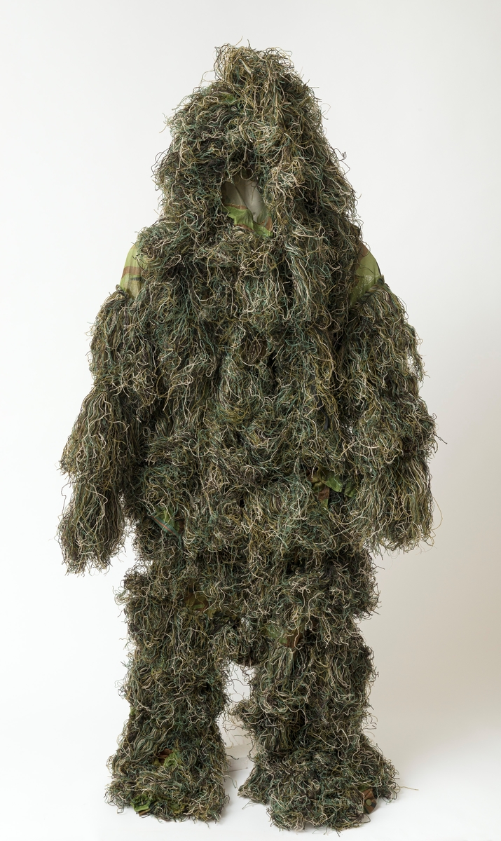 Kamuflasjedress av typen ghilliesuit (Ghillie Suit). Dressen består av jakke, bukse, ansiktsmaske og kamuflasje for våpen og fotoutstyr. Dressen er levert komplett i størrelsen M / L (medium / large). Det medfølger oppbevaringspose til kamuflasjedressen. 