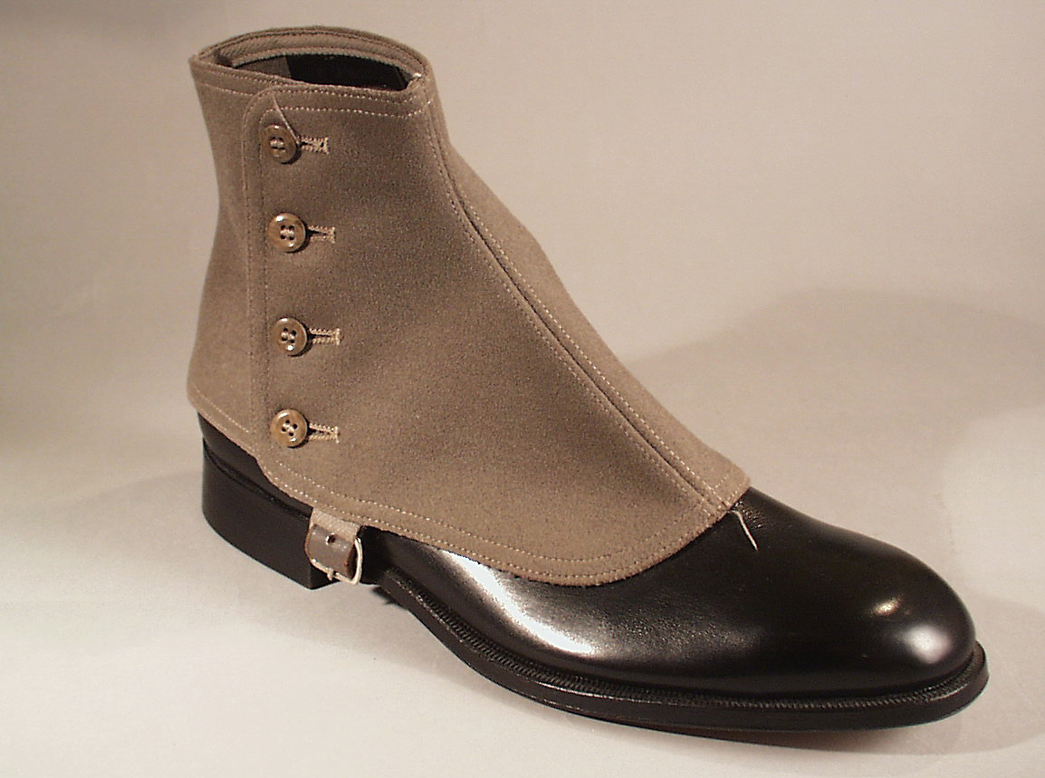 Herrsko, svart skinn av typen "boots" med lågt skaft med sydda sidoresårer. Lädersula och gummiklack. Tillverkare Hästen, Uppsala. Storlek 6½ A, klacken av märket Elg, H-17.Tillhörande damasker av grått kläde, av märket Percival SDE, storlek 42. Knäpps med fyra knappar och skinnrem, med metallspänne, under foten.