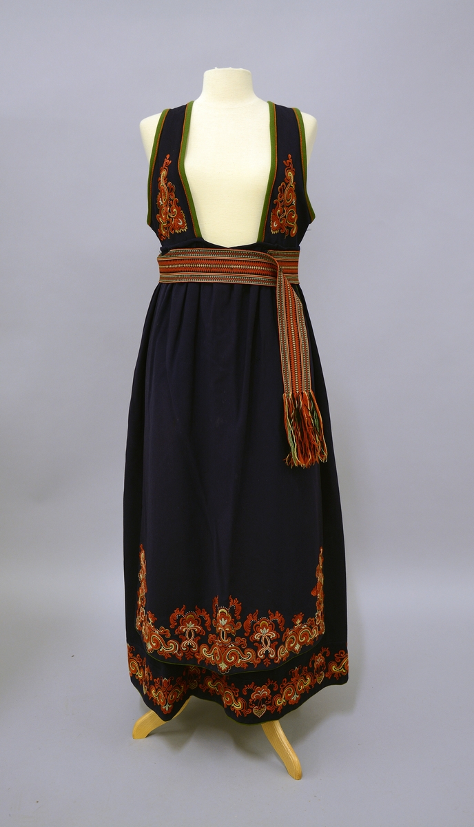 Øst-Telemarksbunad, sydd av Anne Bamle i 1926.TGM-BM.1977:381.A-E 
D. Forkle. Bredde 66 cm nede, opp er det rynket sammen til 34 cm og sydd til en 34 cm lang og 1 cm bred linning, som er tråklet først i stakken. 4 cm nedenfor baugen, slik at brikkebåndet dekker over det. Forkleet er på 3 sider kantet med grønt som stakken nede. Broderiene er dekket av atlas fòr på vrangen. Rosesaum 20cm høy på sidene. 16 cm høy på midten, bygget på samme motiv som stakken. Fra Protokoll.