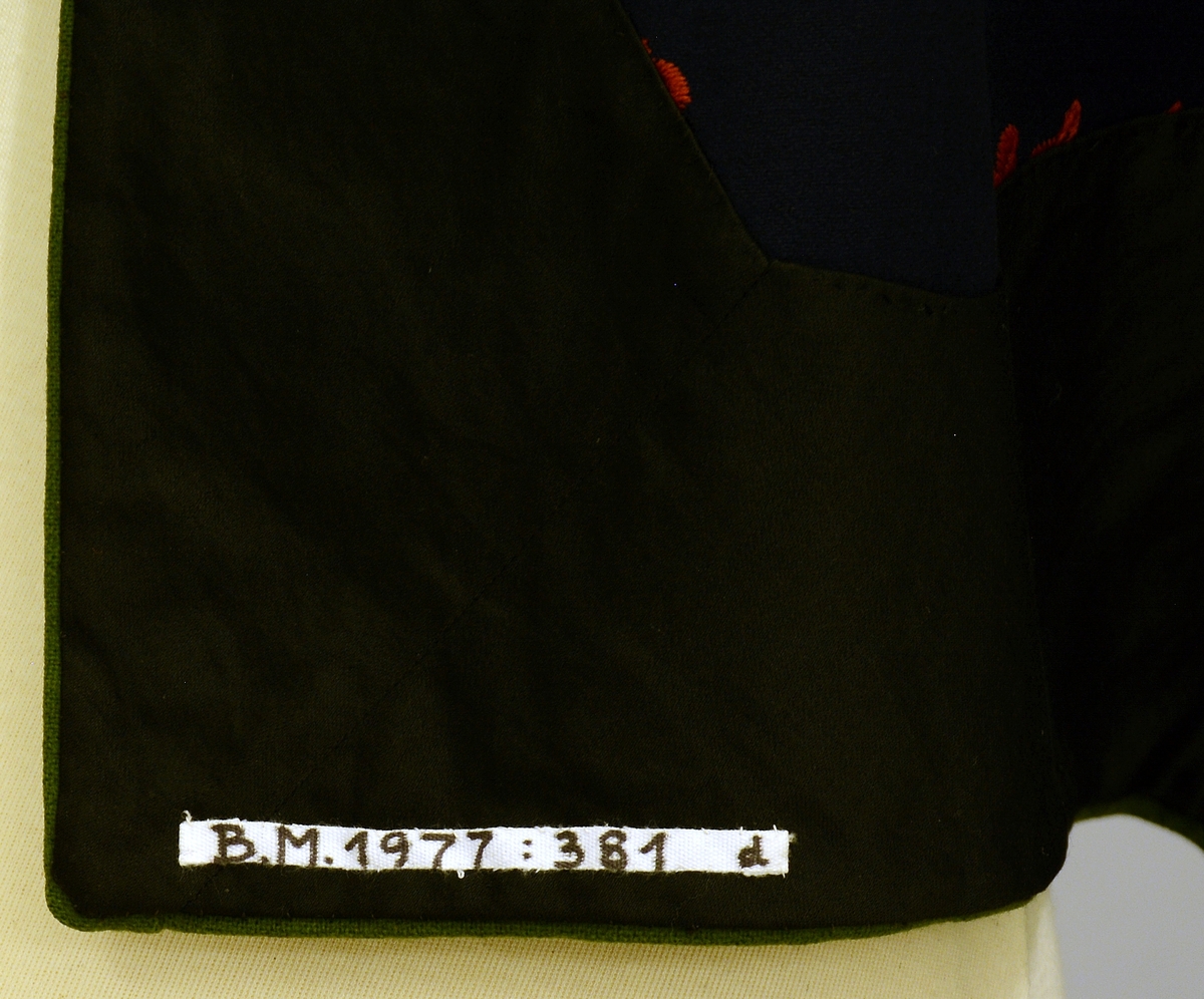 Øst-Telemarksbunad, sydd av Anne Bamle i 1926.TGM-BM.1977:381.A-E 
D. Forkle. Bredde 66 cm nede, opp er det rynket sammen til 34 cm og sydd til en 34 cm lang og 1 cm bred linning, som er tråklet først i stakken. 4 cm nedenfor baugen, slik at brikkebåndet dekker over det. Forkleet er på 3 sider kantet med grønt som stakken nede. Broderiene er dekket av atlas fòr på vrangen. Rosesaum 20cm høy på sidene. 16 cm høy på midten, bygget på samme motiv som stakken. Fra Protokoll.