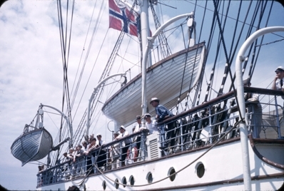 Skoleskipet STATSRAAD LEHMKUHL, livbåter henger i daviter, og passasjerer og offiserer står på broen.