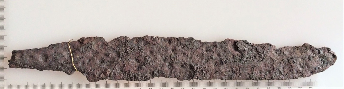 Sverdblad eller stor kniv av jern fra yngre romersk jernalder.  Funnet i en kvinnegrav på Vestby under Evang i 1885