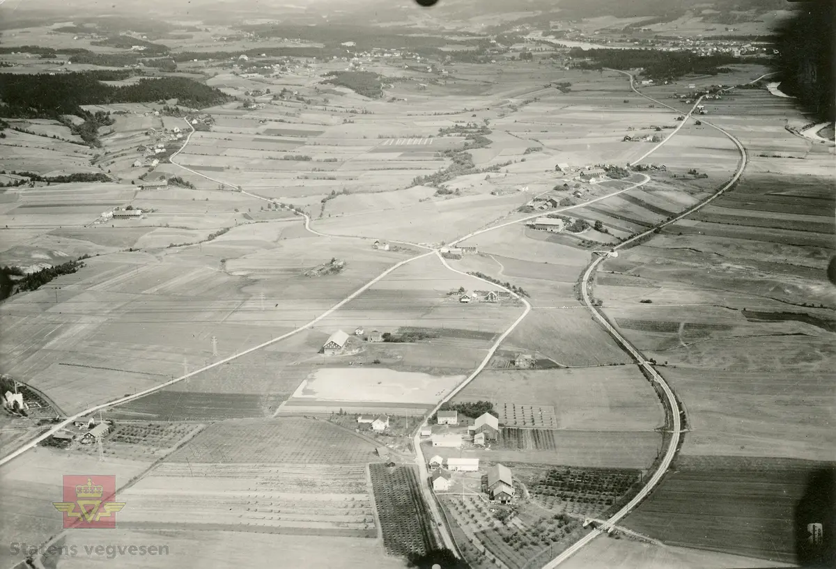 Flyfoto tatt av "Hærens flyvesen og luftforsvar" i 1928. Bildet er i brev fra Vaabeninspektøren for Hærens flyvesen og luftforsvar, datert 12.10.1928, klassifisert som hemmelig bla. fordi jernbane, tettsteder og veganlegg vises. På baksiden av bilder er skrevet følgende: "Nr 21 Fot. av kapt. Lunde, Avd: S.F.A. Dato 30-7-1928 kl: 10:35. Enkelt skråbil. Bar mark. App: Zeiss Br vidde: 25 Form: 13x18. Høide: 700 m. Stedets navn: Vestfossen - Hokksund, tatt mot nord tatt fra vestfossen 2 km syd for billede nr 20.  Kart: Eiker gradavdelingskart." Omslagsark stemplet J.no 3666 1928 G.E.0523-1928