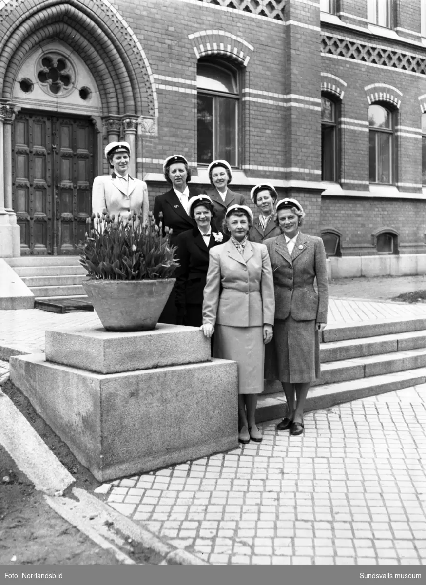 Sju damer som firar sin studentexamens 25-årsjubileum. Gruppfoton utanför Flickskolan.