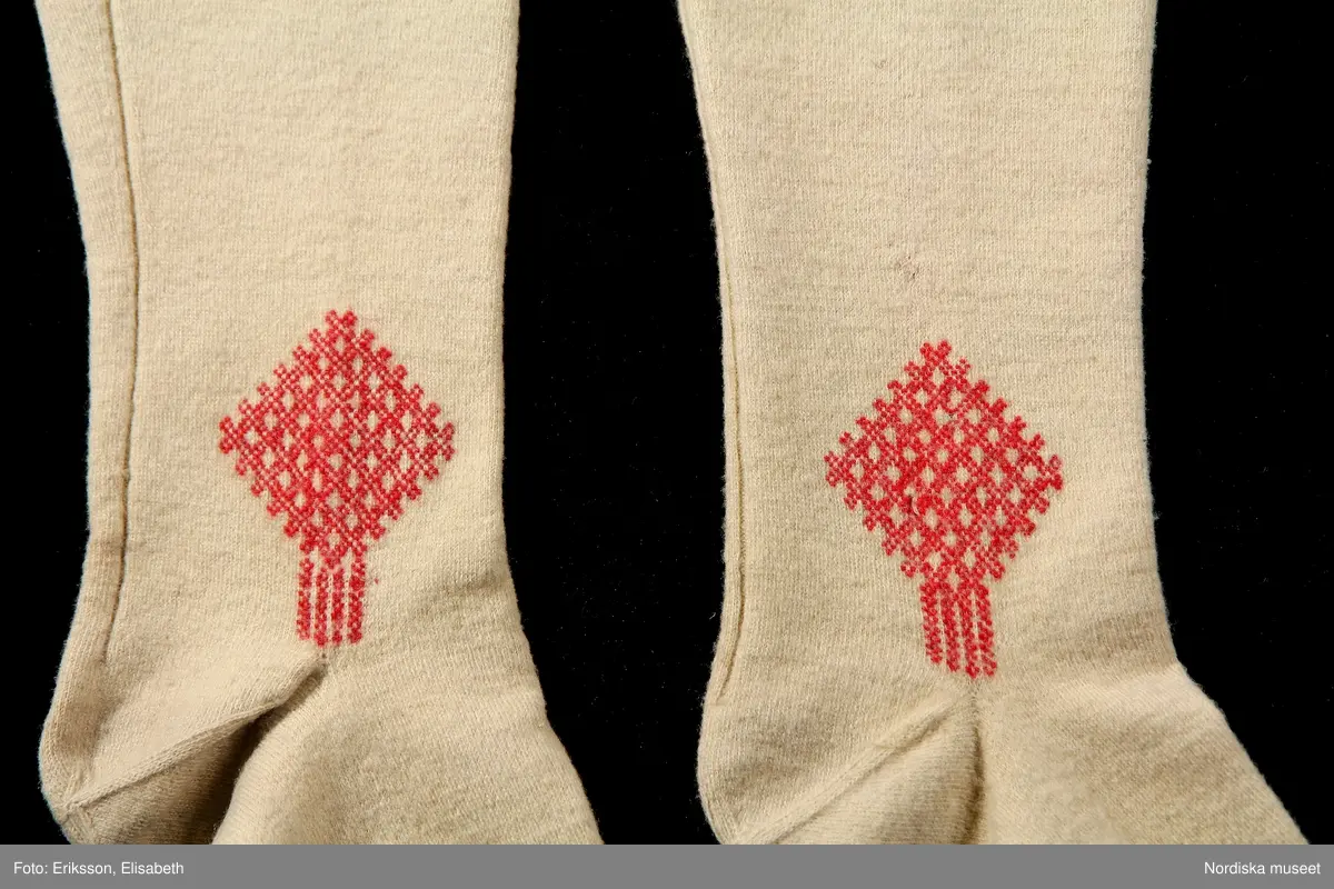 Mansdräkt i flera delar a-d.

a. Rock av svart vadmal
b. Röd väst
c:1-2 Vita strumpor
d. Knäbyxor av sämskskinn
Katalogkort finns.

a. Långrock av svart vadmal. Framstyckena/sidstyckena helskurna, ryggstycket smalt och kort,  avkuret i midjan, rikt veckat bakskört försett upptill med två ulltofsar och med pikerade klaffar en vid var  sida om skörtet. Svängda ärmar med 2 sömmar och blindslag med sprund oknäppt med 2 hakar och hyskor. Ståndkrage. Skoning av hemvävda ylleband i flera färger längs livets insidor, knäppning med hakar och hyskor.
"Dylika rockar tillhörde högtidsdräkten, vid mindre fester och till kyrkan brukades grå rockar af liknande snitt, ett snitt som gaf anledning till benämningen ´fiolen´för nysockenströjans ryggtafla ".
b. Väst av röd vadmal med ryggstycke av grovt oblekt linne i spetskypert. Hög ståndkrage och utvikta slag, med en uddklippt vadmalsremsa i kanten, dubbelknäppning med  vitmetallknappar, fästa på insidan med skinnremsa, knapphål tränsade med grönt ullgarn. 2 sidfickor med list. Foder av oblekt linnelärft, på kragens insida en bit av ryggtyget mitt bak.
c:1-2 . Strumpor slätstickade i tvåändstickning av fint vitt 1-trådigt ullgarn. Uppläggningsvarvet med rött och vitt ullgarn,  smal mönsterstickad överkant. Häl och tå av annat naturgrått garn. Mitt bak en sömmarkering med en avig maska. Vid anklarna broderade rombiska figurer i genombrutet mönster, kallas "löver" i rött ullgarn.
d. Knäbyxor av gult sämskskinn, med bred lucka med 5 knapphål, midjegjord knäppt med 2 knappar. Knapparna är av flera olika sorter av mässing, en av hängselknapparna av horn, 2 bak saknas. Midjegjorden fodrad med linnelärft. Knäsprund knäpps med 4 hakar och hyskor. Flikar vid sprunden uddklippta.
/Berit Eldvik 2010-01-08
